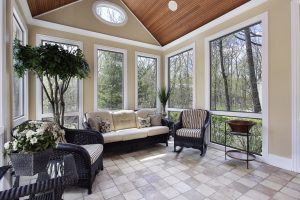 Bright sunroom in a luxury home featuring a large circular window, elegant seating, natural light, and clean modern finishes throughout the space